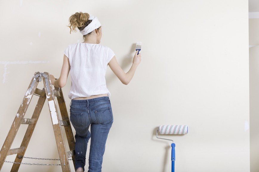 Women painting wall white