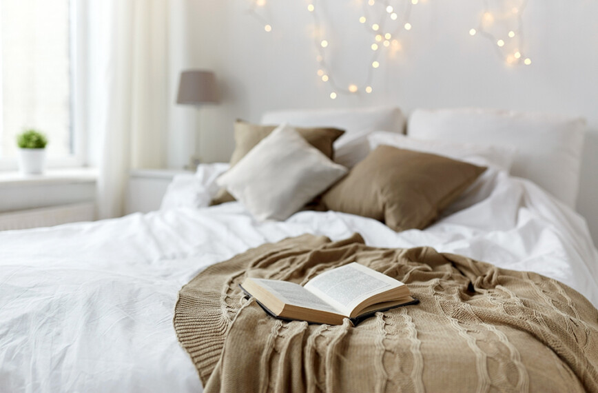 Peaceful bedroom with white bedding and brown sheet. Plus fairy lights