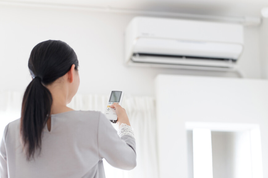 Women using the remote controls to air conditioning unit