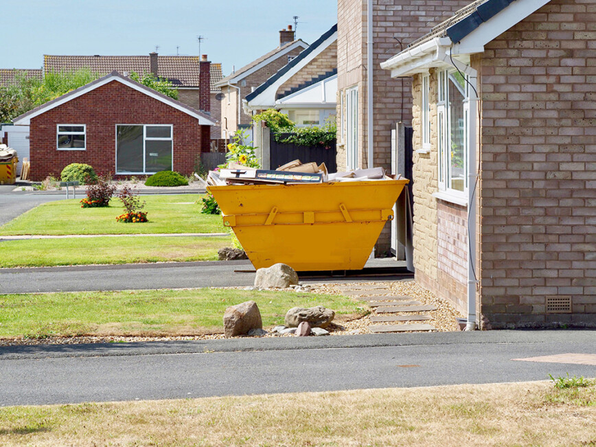 Yellow Skip bin outside on drive of bungalow
