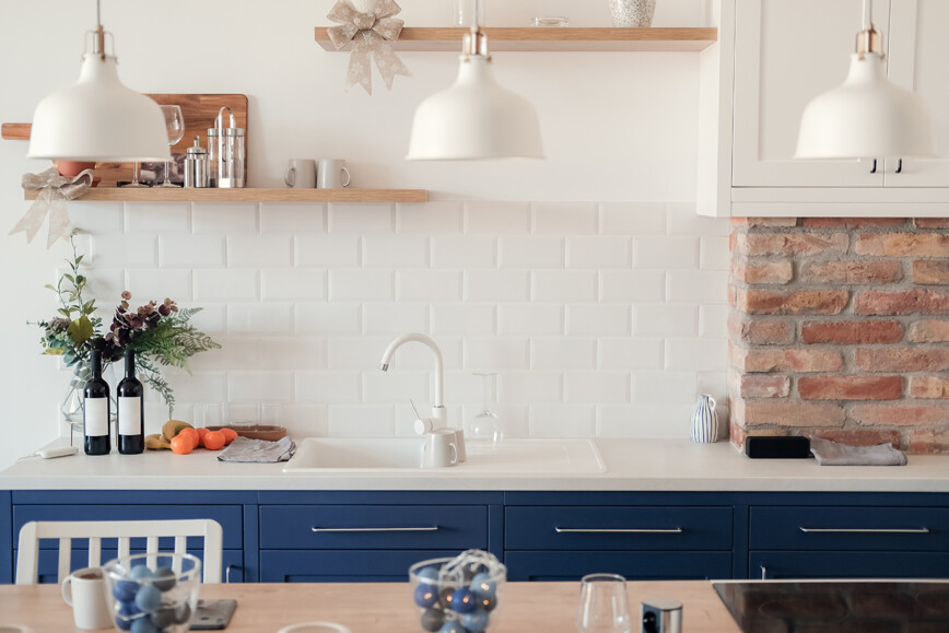 White kitchen with blue kitchen cupboards and three white pendent lights