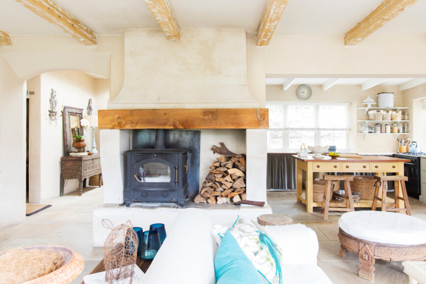 Country cottage decorated in white and wooden beems. Wood buring fireplace.
