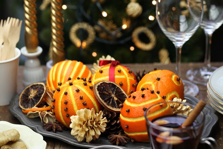 Christmas table decoration. Candels and wine glasses, with a decorative centre piece made of scented spiced orange pomander balls.  