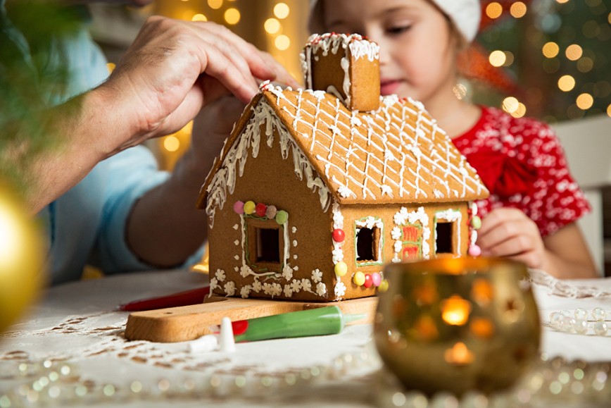 Father and daughter decorating Christmas Gingerbread House