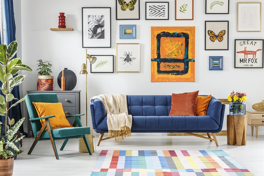 Colourful living room with blue sofa, multicoloured rug, and picture wall